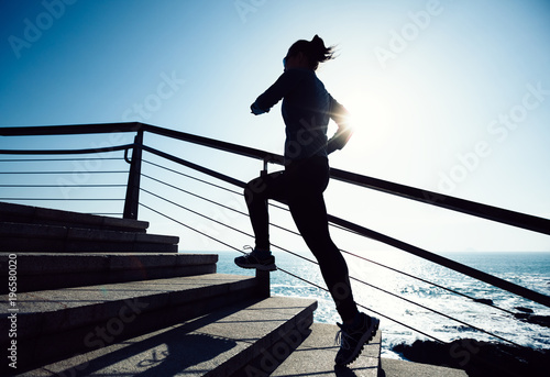 sporty female runner running upstairs on coast trail