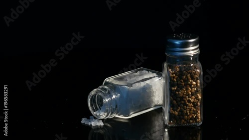 Sea Salt and Black Pepper displayed in glass Jars on black backgound photo