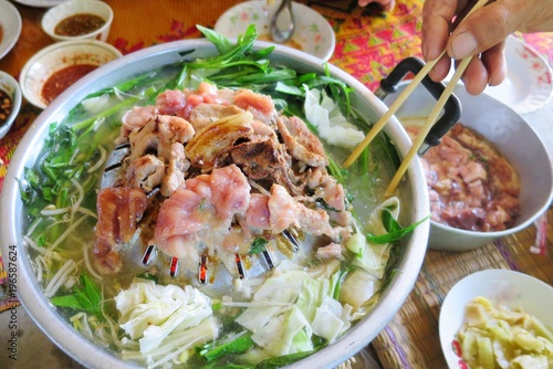 Hand use chopsticks grilled pork on the pan in thai style. Thai Barbeque is faverite food for party. Food concept. photo