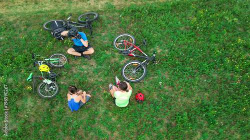 Family cycling on bikes outdoors aerial view from above, happy active parents with child have fun and relax on grass, family sport and fitness on weekend

