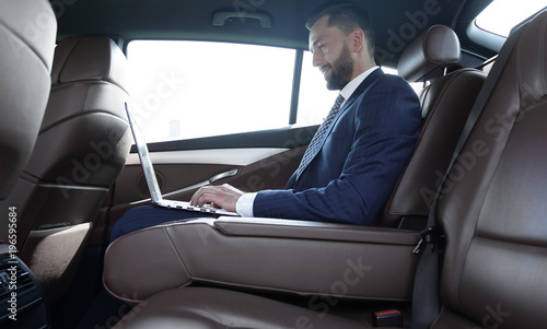 confident businessman sitting on the backseat of a prestigious car © ASDF
