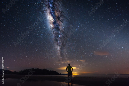Rear view of man and Milky Way Galaxy at the beach. Image contain soft focus  blur and noise as night photo required long expose and high ISO.