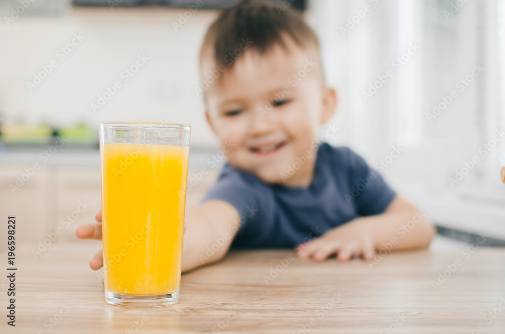 A charming little boy tries to reach the juice of orange A charming little boy tries to reach the juice of orange