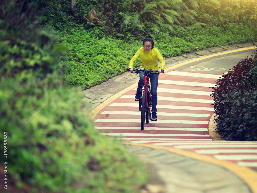 woman cyclist riding bike on forest trail woman cyclist riding bike on forest trail