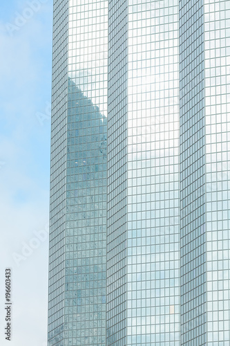 Business abstract - modern office building covered with glass against blue sky. Copy space. Details of architecture