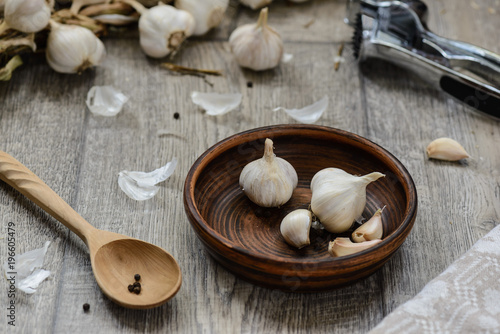 garlic in a clay bowl with a wooden spoon and chop the garlic on a table