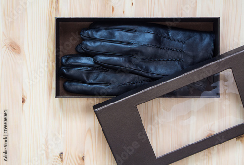Black leather gloves in premium cardboard box on wooden table