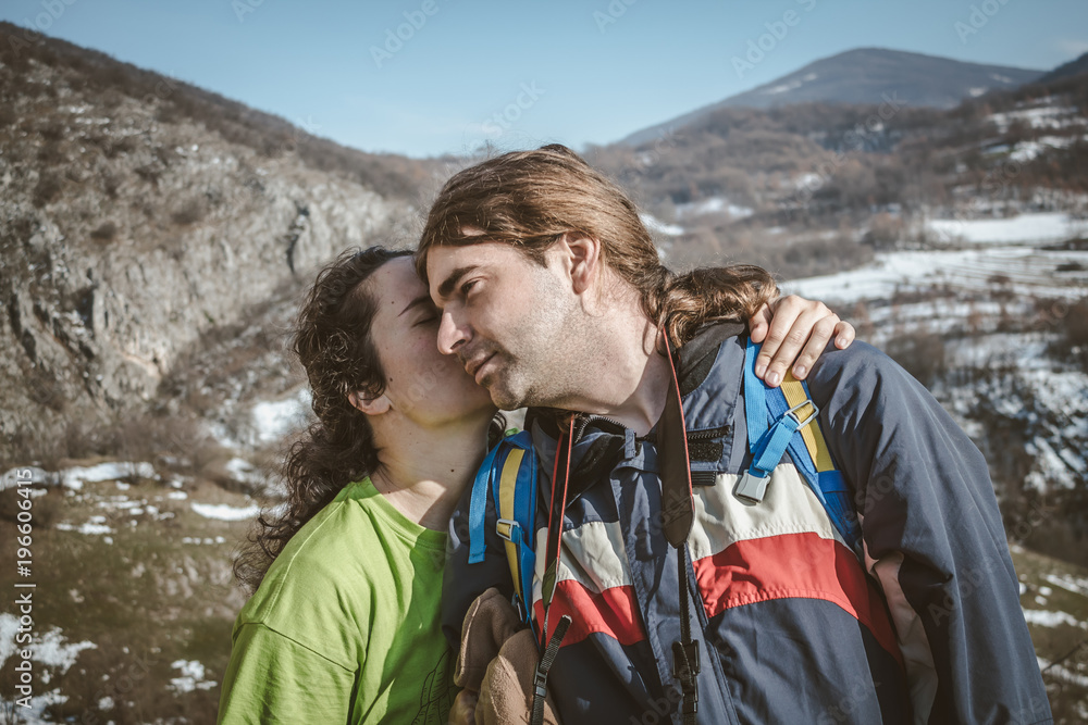 Couple of hikers on the mountain cliff. Lover women and men travel relax in the holiday enjoying on the mountain and hugging.