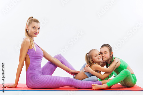 Hatha yoga fitness . Young mother Instructor and daughters exercise gymnastic together. Isolated on white background. Family look.