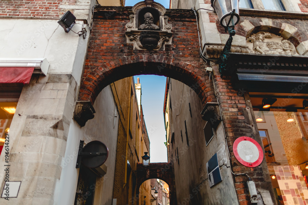 low angle view of arches and narrow street with old houses in brugge, belgium