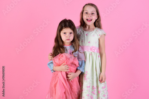 Sisters hold pink cloth. Childhood and family concept.