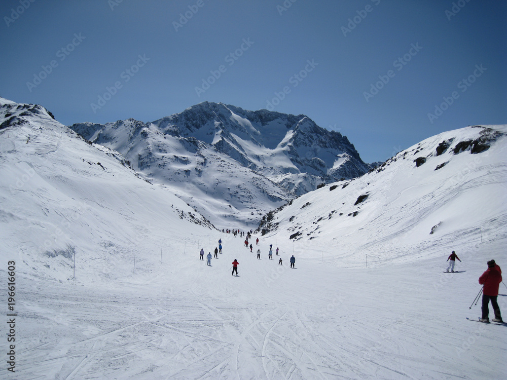 People of all ages ski down a shallow sloping valley in the three valleys ski region of France