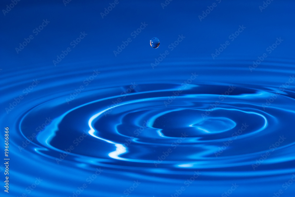 drop of water liquid with splash isolated. the drop explodes in the water sending spray to the sides and circle ripples around it. the water is blue drop of water liquid with splash isolated. the drop explodes in the water sending spray to the sides and circle ripples around it. the water is blue