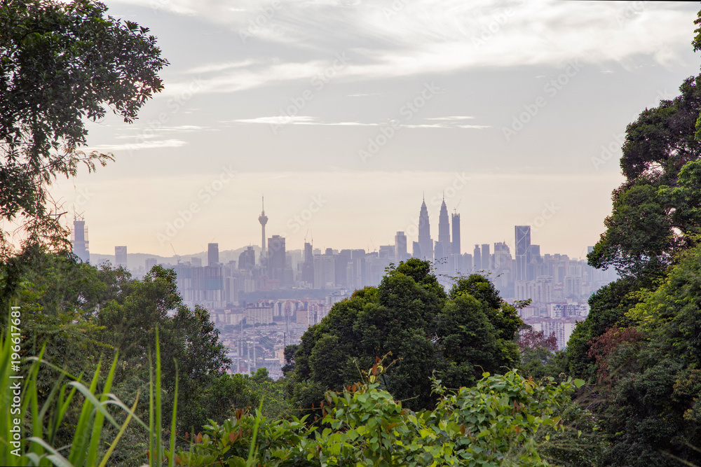Fototapeta premium Kuala Lumpur's famous skyline and skyscrapers in late afternoon framed by the thick jungle vegetation that surrounds the city