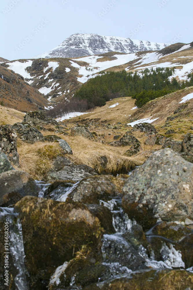 Winter valley with the rocks and orange dry grass with the big mountain with snow in the Island Winter valley with the rocks and orange dry grass with the big mountain with snow in the Island