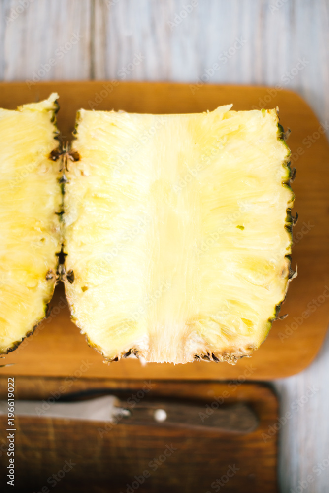 Sliced fresh pineapple on a wooden background in sunlight Sliced fresh pineapple on a wooden background in sunlight