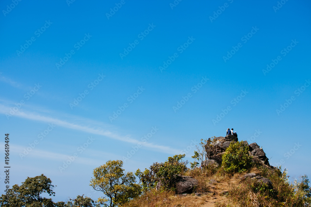 A couple is sitting at the top of a hill A couple is sitting at the top of a hill