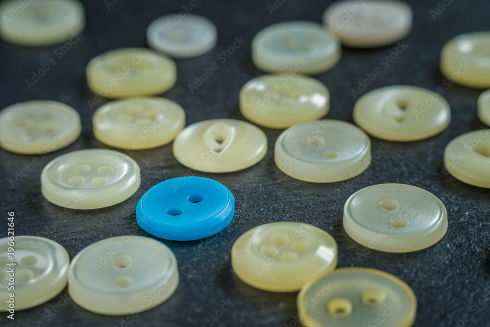Blue button, different from the rest, surrounded by beige buttons. Macro detail. Blue button, different from the rest, surrounded by beige buttons. Macro detail.