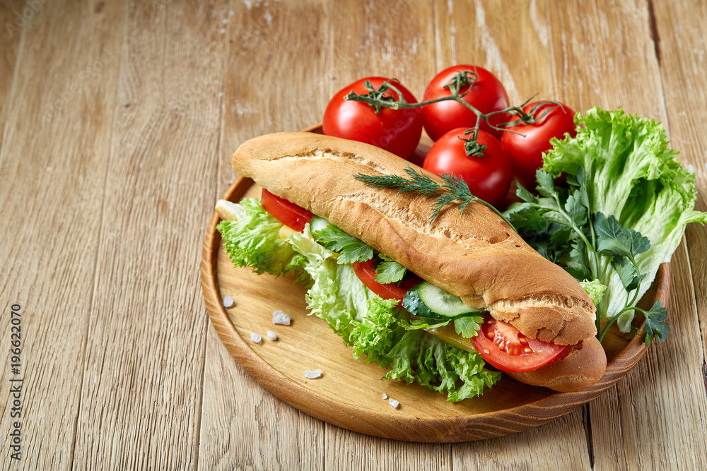 Fresh sandwich with lettuce, tomatoes and cheese served on wooden plate over rustic background, selective focus Fresh sandwich with lettuce, tomatoes and cheese served on wooden plate over rustic background, selective focus