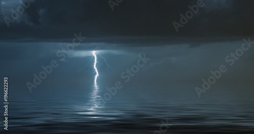lightning bolts reflection over the sea. taken during a thunderstorm over the ocean with clouds in the background © dan
