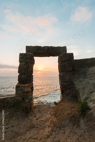 Stone gate towards the ocean with sunrise view.