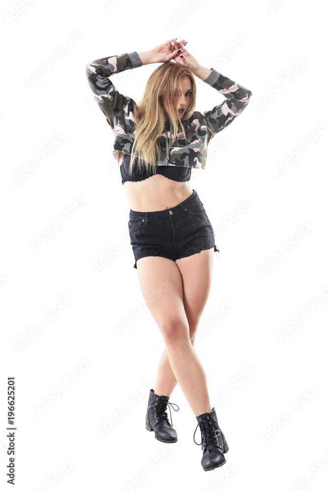 Sexy attractive blonde caucasian woman in military camouflage jacket posing at camera with hands on head. Full body isolated on white background. 