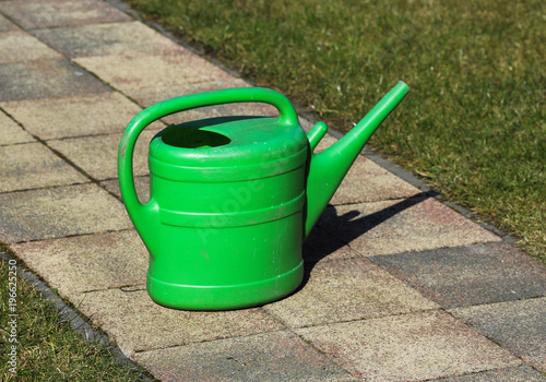 Green watering can in garden