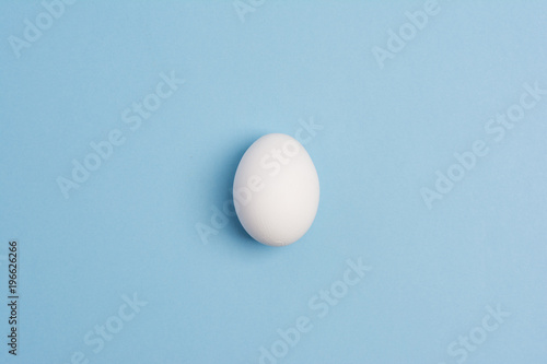 Happy Easter concept. White egg in a row on blue background close up. Flat lay. Minimal concept. Top view. Design, visual art.