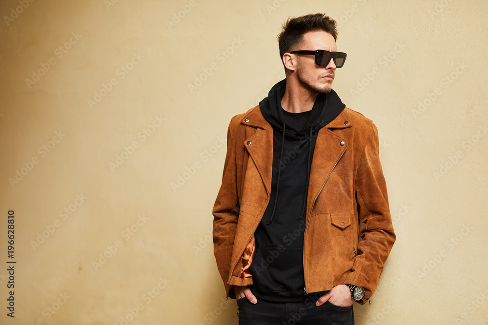 Model looking man stand near the wall and hold his glasses towards the sun shine Model looking man stand near the wall and hold his glasses towards the sun shine