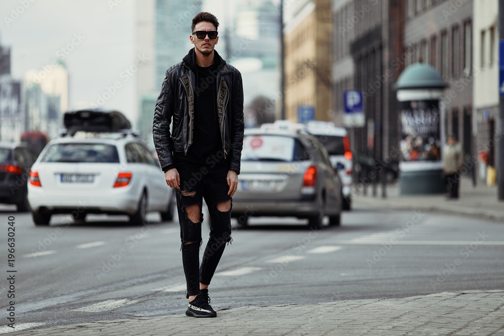 Model looking man stand on the city street with cars background, look on his watch and around