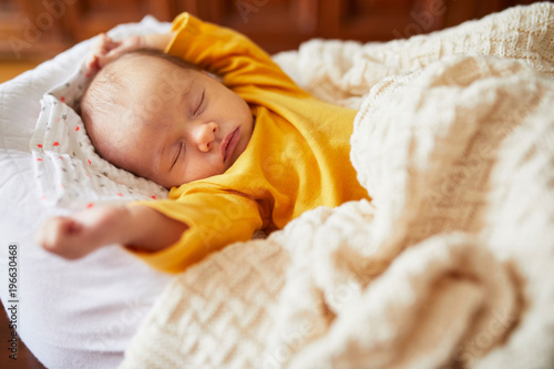 Newborn baby sleeping under knitted blanket