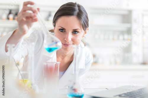 Young, female researcher carrying out experiments in a lab (shallow DOF; color toned image)