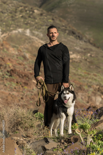 Sportive confident man with dog on rocks © Juan Algar