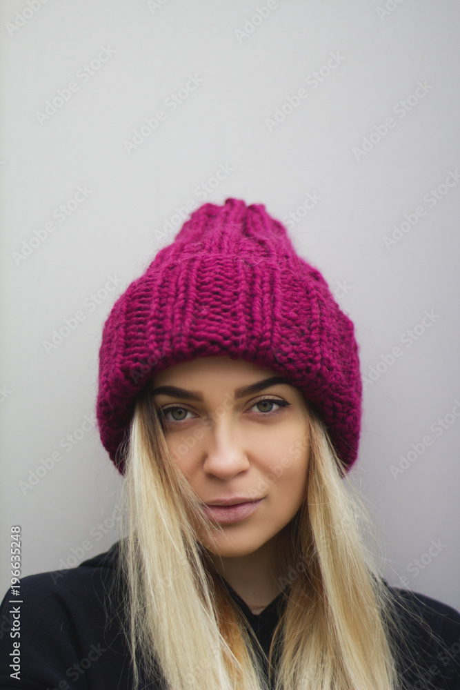 a blonde girl with big eyes and plump lips against a light gray background. a woman in voluminous warm fuchsia-colored caps. a blonde girl with big eyes and plump lips against a light gray background. a woman in voluminous warm fuchsia-colored caps.