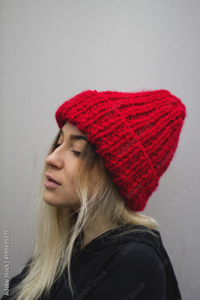 a blonde girl with big eyes and plump lips against a light gray background. woman in a voluminous warm red hat. a blonde girl with big eyes and plump lips against a light gray background. woman in a voluminous warm red hat.