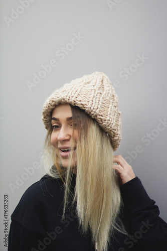  blonde girl with big eyes and plump lips against a light gray background. woman in a voluminous warm beige hat.