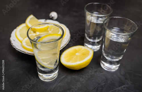 Glass of vodka. And lemon slicing on a plate. Place for your text.