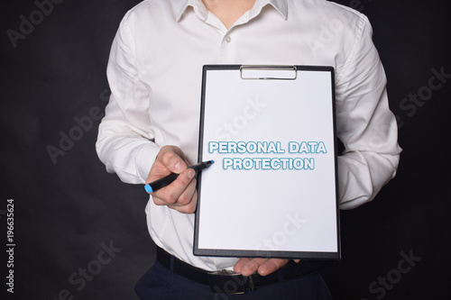 In the hands of a businessman a notebook with the inscription:PERSONAL DATA PROTECTION