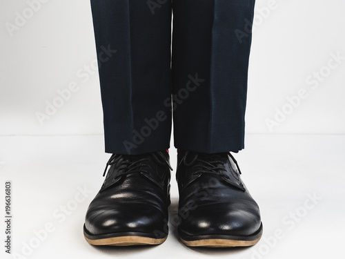 Male legs in stylish, black shoes on a white background. Style, fashion