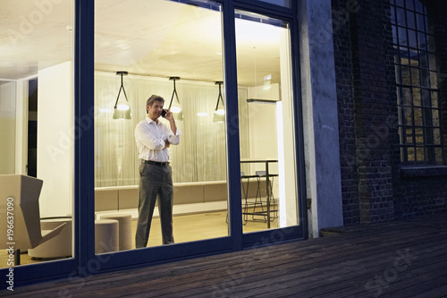 Exterior view of man using smartphone in modern building at night