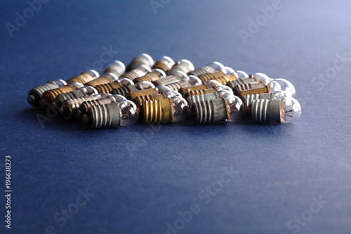 Light bulbs set on blue paper background. Colorful gold bronze and silver vintage lamps. Macro view shallow depth field. copy space photo