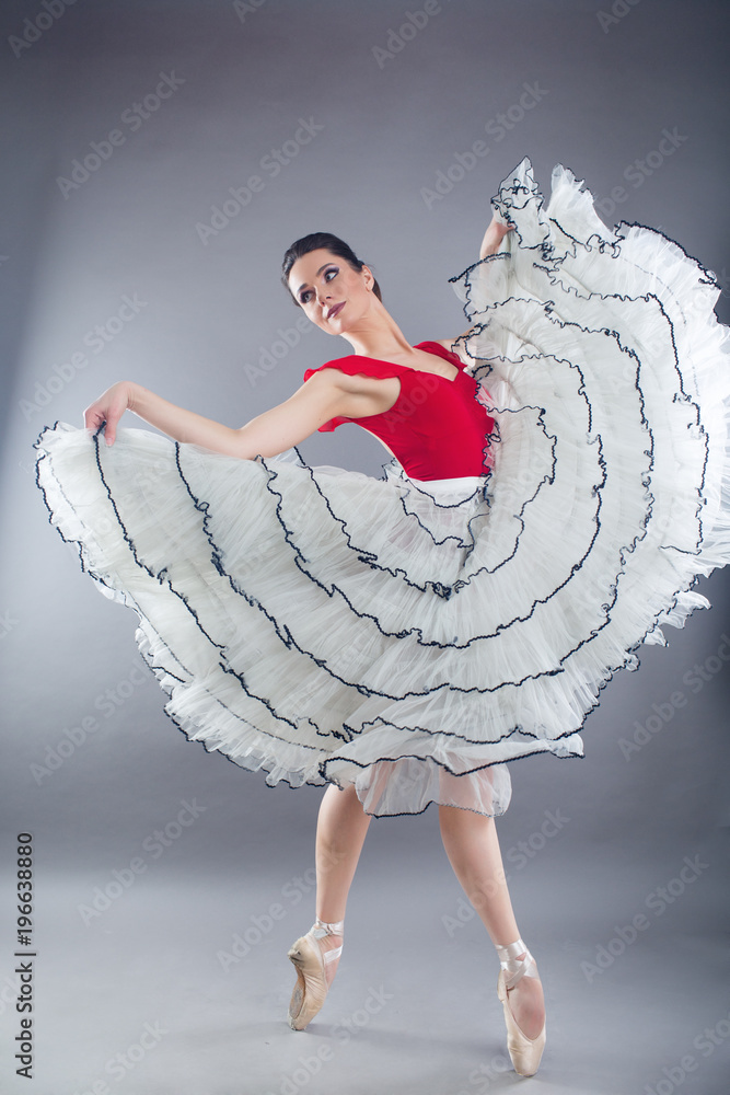 Naklejka premium Beautiful slim woman ballet dancer in studio isolated on gray