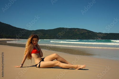 young woman in swimsuit sitting at the beach, Brazil photo