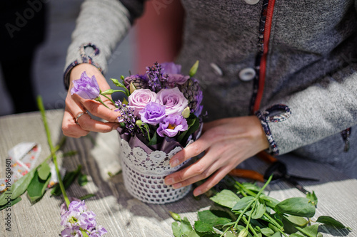 Woman hands making a tender lilac bouquet of flowers on the table