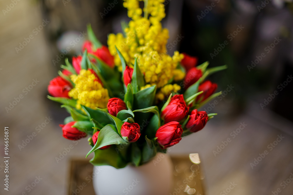 Beautiful red tulips and yellow mimosa in a vase