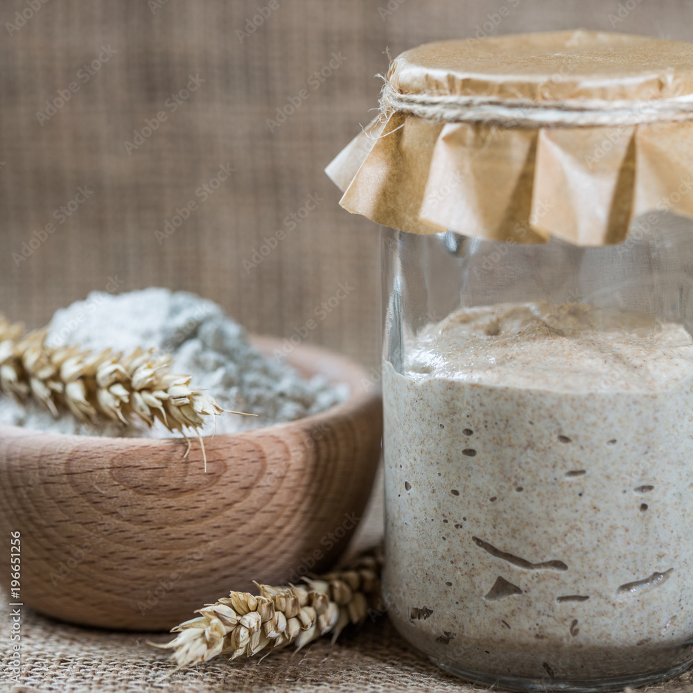 Rye natural leaven for bread in a glass jar. A living product. Spikelets. The concept of a healthy diet. Sourdough starter