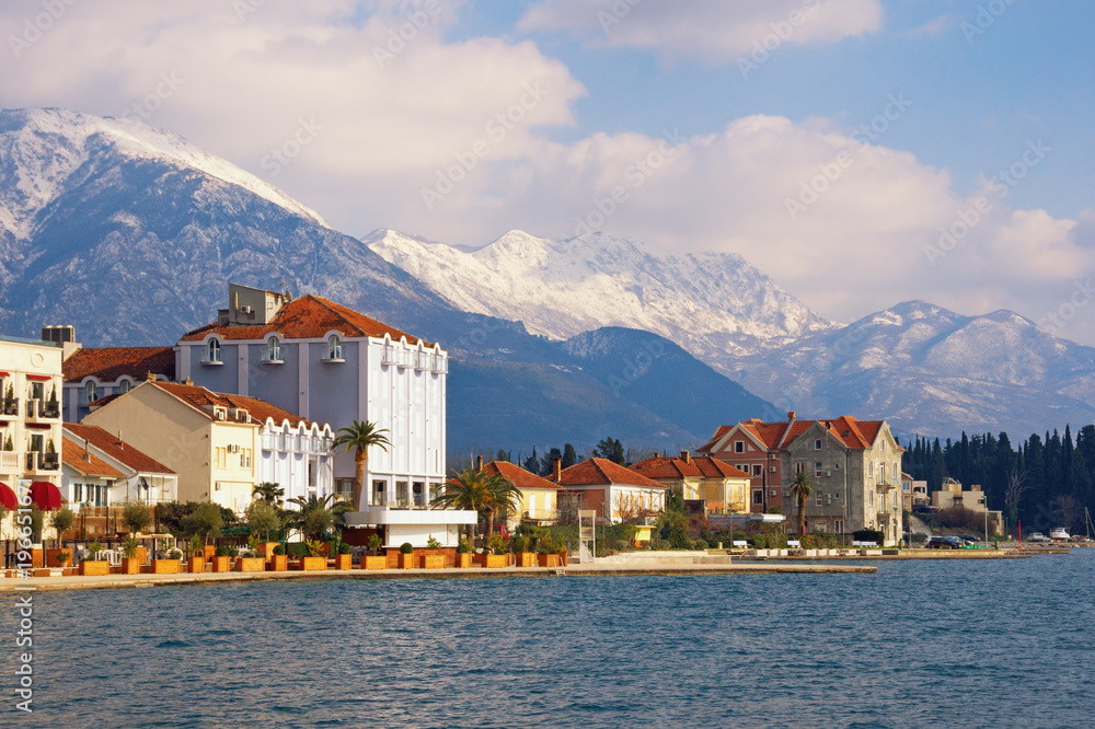 Seaside town at the foot of the snowy mountains. Montenegro, Bay of Kotor, view of embankment of Tivat city and snow-capped peaks of Lovcen mountain
