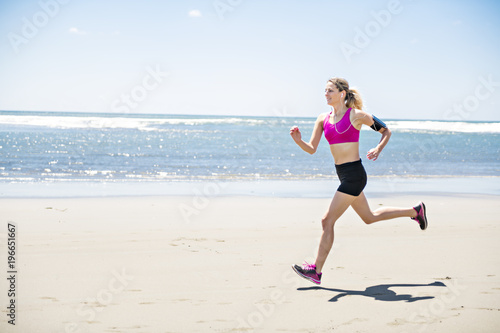 Young woman jogging on the beach in summer day. Athlete runner exercising actively in sunny day © Louis-Photo