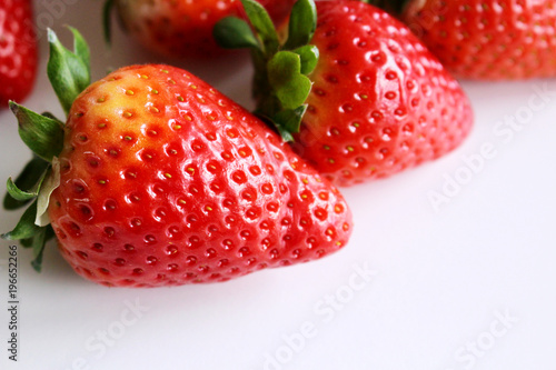 Food background .Closeup on a freshly organic red ripe strawberries lying on a white background.Summer ripe berries.Delicious fruit. Space for text in corner .Blurred background.