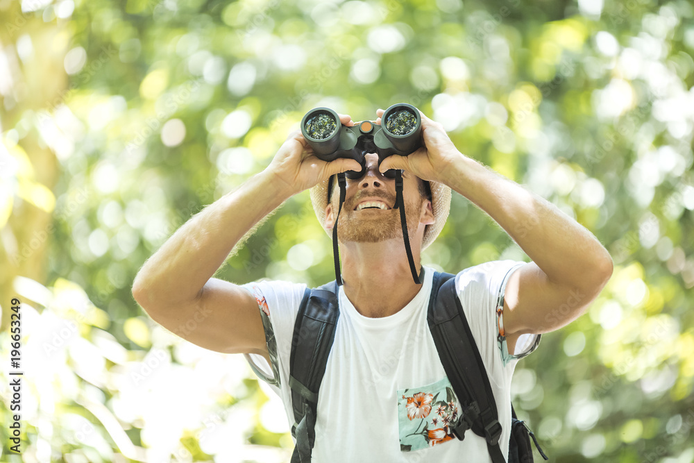 Tourists man with Binoculars Looking for something along the forest Tourists man with Binoculars Looking for something along the forest